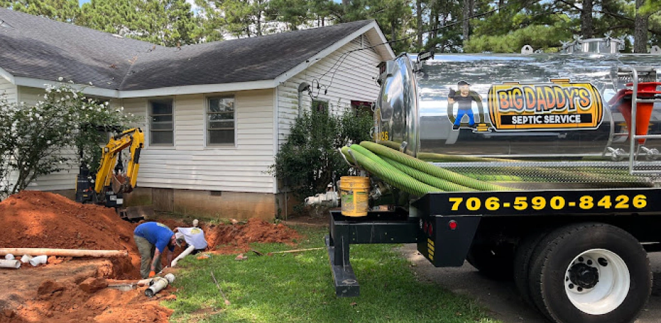 workers installing a new septic line outside of a beige siding house